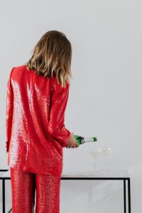 Kaboompics - Woman in a red jacket holds a bottle of champagne