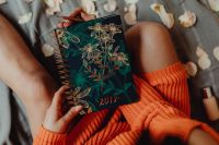Kaboompics - A woman in an orange sweater holds the 2019 calendar in her hands