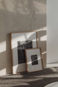 Two framed pictures leaning against a textured wall