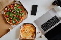 Kaboompics - Top view of the desk with pizza, laptop, phone and hands