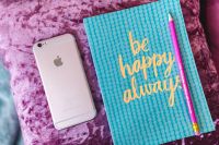 Blue notebook with a pink iPhone and a pencil