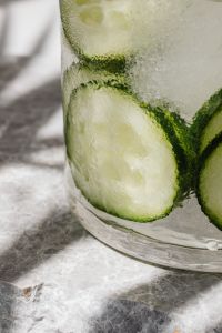 Water glass - cucumber - ice cubes - marble - closeup - close-up - close up
