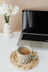 Laptop - white flowers & cup of coffee on marble table