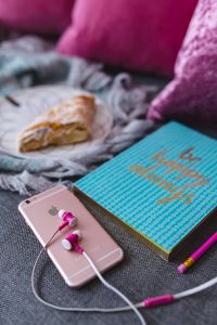 Kaboompics - Blue notebook with a pink iPhone, headphones and a sweet bun