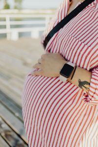 A pregnant woman with a smartwatch on her hand
