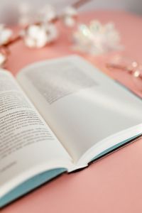 An open book, a cotton branch on a pink background