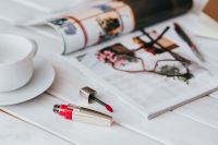 Coffee on table with a magazine and a lipstick