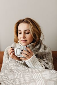 Cocooning - isolating yourself - staying at home - a woman under a blanket - tea time