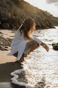 Kaboompics - Faceless Woman Crouching by Rocky Shore at Golden Hour