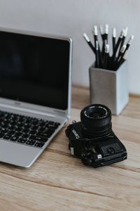 Black-and-white photos with a silver laptop, a smartphone, car keys, pencils and a camera