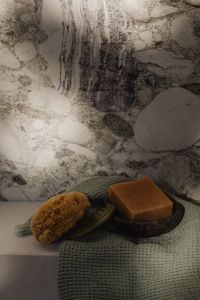 Kaboompics - Sea Sponge and Handmade Soap on Green Textured Towel Against Marble Wall