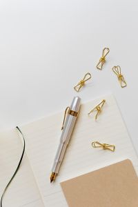 Kaboompics - Fountain Pen Nib, Gold Clips and Lined Notebook in a Minimal White Workspace, Vertical Detail
