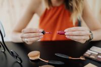 Kaboompics - Hands Holding Lipstick and Applicator Beside Makeup Brushes and Eyeshadow Palette