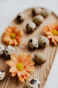Kaboompics - Soft-Focus Quail Eggs and Orange Flowers on a Wooden Tray, Vertical Easter Background