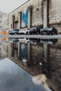 Kaboompics - Parked Cars Reflected in a Puddle beneath Weathered LX Factory Wall Art, Lisbon, Portugal
