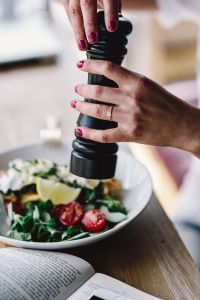 Kaboompics - Close up of female hands flavouring salad in a bowl