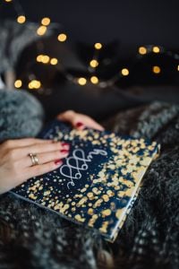 Kaboompics - Hands Resting on a Hygge Book in a Cozy Reading Scene