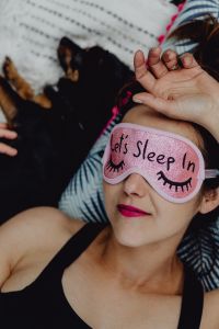 Kaboompics - Joyful girl relaxing in bedroom - top view of brunette women in pink sleeping mask