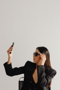 Kaboompics - Businesswoman Adjusting Sunglasses While Holding a Smartphone