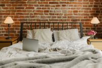 Kaboompics - Work From Bed Scene with Laptop, White Bedding, Lamps and Pink Flowers