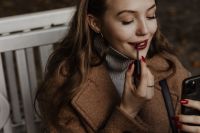 Kaboompics - Woman Applying Red Lipstick with a Smartphone as Mirror
