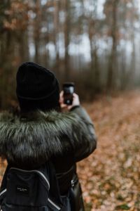 Kaboompics - A woman takes a picture with her iPhone X in the autumn forest