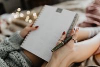 Kaboompics - Writing in a notebook lying in bed, with coffee, candles, and gingerbreads