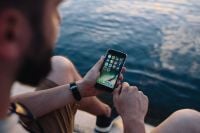 Kaboompics - Seated Man Browsing a Smartphone Beside Rippling Seawater