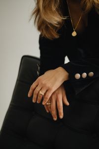 Kaboompics - Woman Sitting in Black Chair with Gold Rings and Necklace