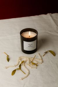 Kaboompics - Black Candle with Pearls and Dried Leaves on Burgundy Backdrop
