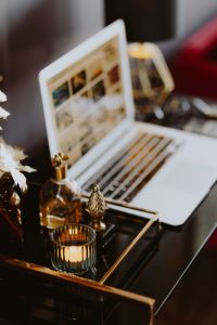 Kaboompics - Close-Up Laptop Desk Scene with Gold Perfume Bottle and Candle
