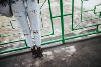 Kaboompics - Blonde woman in a black jacket and ripped jeans by a green handrail