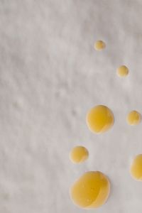 Kaboompics - Golden Skincare Oil Drops Scattered on a Soft Beige Background