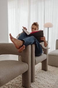 Kaboompics - Woman Reading a Book in a Neutral Armchair