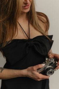 Kaboompics - Woman Holding a Compact Camera Against a Black Dress