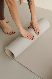 Kaboompics - Hands Rolling a Yoga Mat Across the Floor