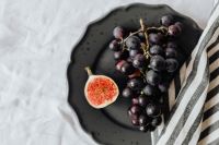 Kaboompics - Fresh Fig and Dark Grapes on a Black Stoneware Plate, Moody Food Styling Still Life