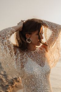 Kaboompics - Woman Wearing Statement Earrings in Sequin Dress at Sunset