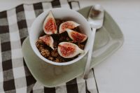 Kaboompics - Granola and Fresh Figs in a White Bowl on a Square Plate with Spoon and Gingham, Copy Space