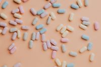 Kaboompics - Pastel Sugar-Coated Candy Pieces Scattered on Peach, Minimal Dessert Background
