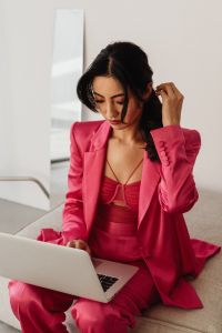 Kaboompics - Woman Using Laptop on Sofa in Pink Satin Suit