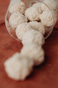 Kaboompics - Shallow-Focus Coconut Truffles in a Tipped Glass, Close-Up Dessert Still Life on Rust Linen