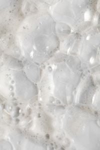 Kaboompics - Translucent Oversized Soap Bubbles over White Skincare Foam, Glossy Macro Texture