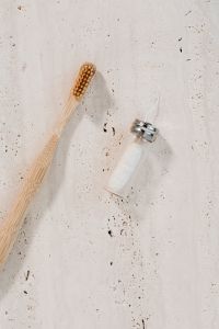 Kaboompics - Bamboo Toothbrush and Glass Floss Dispenser on Warm Limestone for Sustainable Oral Care