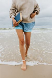 Kaboompics - Close Crop of a Woman Carrying a Book as She Steps Through the Shore Break, Barefoot Summer Beach