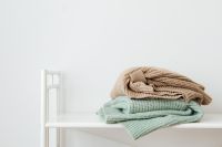 Kaboompics - Folded Pastel Sweaters on a White Shelf With Copy Space