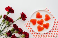 Kaboompics - Red Carnations and Heart-Shaped Gummies on White Paper