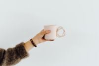 Kaboompics - Horizontal Hand Holding a Pink Mug Against White Copy Space