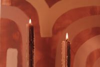 Kaboompics - Lit Taper Candles Against an Abstract Terracotta Painting, Close-Up
