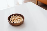 Kaboompics - Wooden Bowl of Cashews on White Table with Copy Space for Menu Design